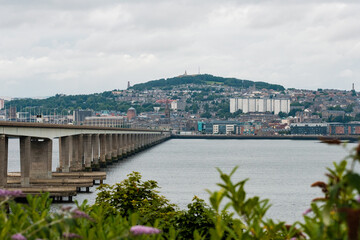 Dundee Scotland: 4th Aug 2024: The Tay Bridge stretches over a calm body of water with a cloudy sky...