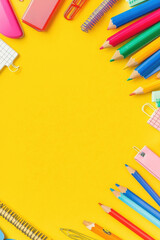 Fototapeta premium Bright and colorful stationery items arranged on vibrant yellow background create cheerful and inviting workspace. Perfect for school or office use