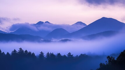 Fototapeta premium A foggy sky in the early morning with low clouds hanging over a mountain range, shrouding the peaks in mystery