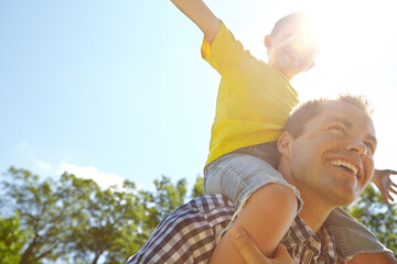 Father, son or carrying on shoulders in park for fun games, summer break or bonding in low angle...