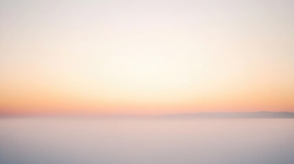 Fototapeta premium A soft hazy sky at dawn with muted orange and pink hues blending into the misty horizon, creating a tranquil and dreamy atmosphere
