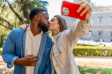 Naklejka premium Couple kissing while taking selfie in a city park