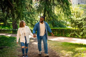 Fototapeta premium Happy casual multi-ethnic couple walking together in a park