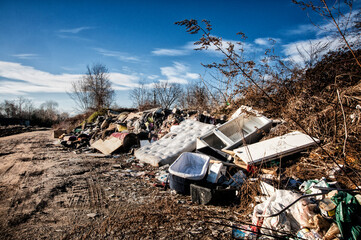 Alla periferia della città rifiuti ed immondizia abbandonata sul cilio di una strada.