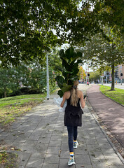 woman walking on street with plant