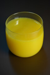 Beautiful and unusual photos of food products. Bright yellow, orange, orange, multi fruit juice poured into a transparent thin small glass.