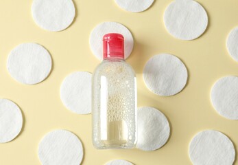 Micellar cleansing water and cotton pads on a color background, top view. Flat lay.