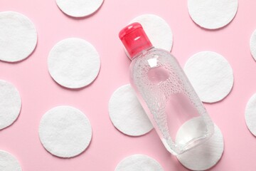 Micellar cleansing water and cotton pads on a color background, top view. Flat lay.