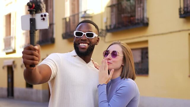 Multi-ethnic couple using mobile phone handheld gimbal for vlogging outdoors