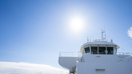 A close-up view of a ship's bridge with the sun shining high in the blue sky. The scene offers negative space, ideal for designers looking to add text or overlay elements