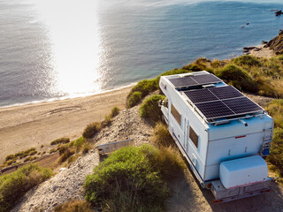 Caravan with solar panels on roof camp on sea, Spain. Aerial view.