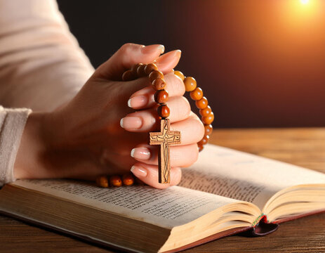 Rezando una oracion sobre la biblia con un rosario y una cruz en las manos