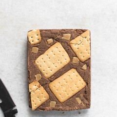 Overhead view of chocolate fudge with cookies and fudge on a white tray, Top view of hazelnut chocolate fudge slab on a white granite countertop