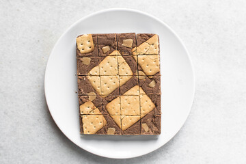 Overhead view of chocolate fudge with cookies and fudge pieces on a white plate, Top view of hazelnut chocolate fudge cut into pieces, fudge cookie candy on a white granite countertop