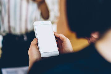 Dark haired woman interacting with smartphone in office