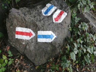 Blue and red arrow shaped hiking trail signs painted on a rock