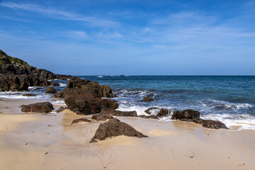 Rocks on the sandy beach at Portheras Cove on the Cornish coast
