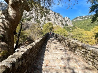 Photo of a charming stone path on top of the Portaikos Bridge, which crosses the Portaikos River in Trikala, Thessaly, Greece. This historic bridge is part of the UNESCO Global Geoparks.
