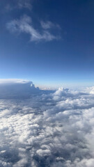 Fototapeta premium View above clouds on blue sky background. View from airplane window.