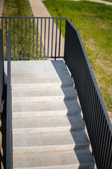 Staircase leading to the entrance of a multi-story residential building on a sunny day with grassy...