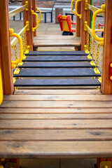 Modern children's playground in a residential neighborhood with wooden structures and bright yellow...