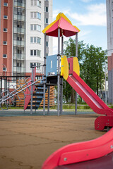 Modern children's playground with colorful slide and climbing structure in a residential area under a clear blue sky