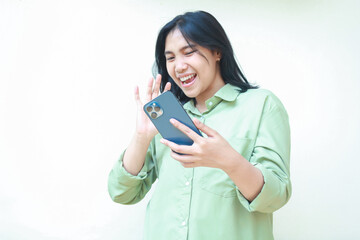 confident ecstatic success asian woman dark haired raising palms say hi gesture to smartphone hold on hands wearing green over size shirt standing isolated white background, welcoming expression