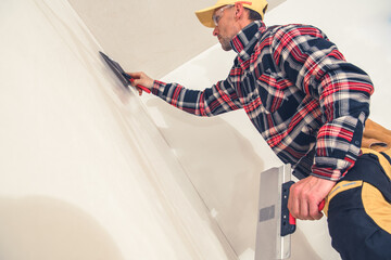 Skilled Worker Applying Finishing Touches to a Wall Indoors During Home Renovation Project