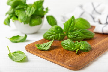Green basil leaves on a textured wooden background. Kitchen herbs, spices. Fresh green organic basil. Vegan. Greens for salad. Place for text. Copy space.
