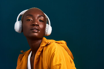 Black woman, headphones and portrait with exercise, workout and fitness playlist in studio. Streaming, radio and health with training and wellness with internet song and music with dark background