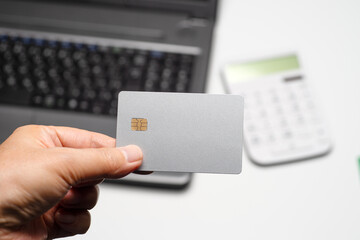 ノートパソコンと電卓とシルバーのクレジットカード