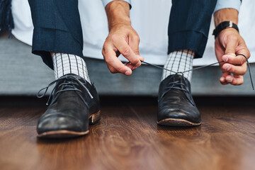 Business, hands and tie shoes in home on bed with getting ready, dressing for work or morning routine in bedroom. Professional, man and employee with designer footwear in apartment for startup career