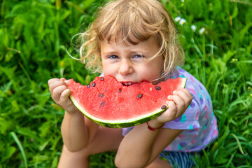 Child eats watermelon in summer. Selective focus.