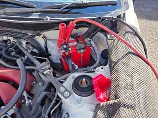 ジャンプスターターが繋がれたクルマのバッテリー