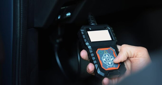 car mechanic using OBD2 scanner, code reader tool to check engine errors and for diagnostics