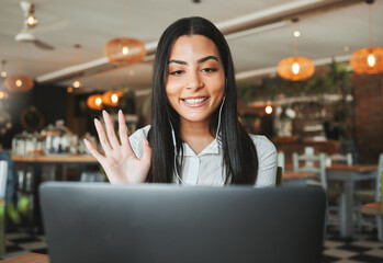 Woman, video call and wave with laptop at coffee shop for virtual meeting, hello and earphones with remote work. Person, journalist and happy at cafeteria, greeting and online interview for article