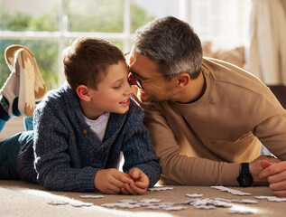 Father, son and play with puzzle at house for problem solving, learning and connect pieces of education. Smile, family and jigsaw fun with creative development, bonding together and childhood support