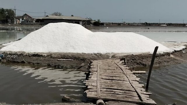 A pile of salt harvest is located in front of the salt field pond in Tambak Cemandi Village, Sedati District, East Java, Indonesia.