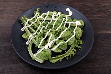 皿の上の茹でてマヨネーズをかけたコゴミのアップ