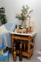 Izmail, Ukraine. December 2023. Beautiful Christmas decorations, lantern, bulbs and candles, vase with fir branches. Plaid and cushions. Bottles with candles on floor