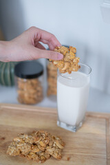Close-up hand holding homemade baking cookies snack dipping into glass milk drink perfect for...