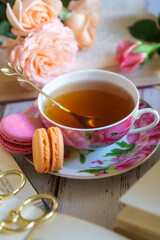 Beautiful roses, a cup of tea and many books on the table.