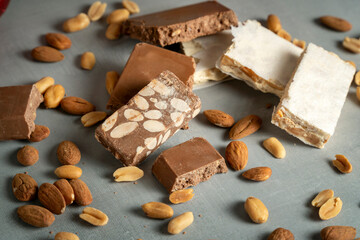 A selection of nougat bars richly filled with almonds and peanuts, arranged on a flat surface,...