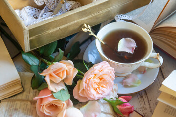 Beautiful roses, a cup of tea and many books on the table