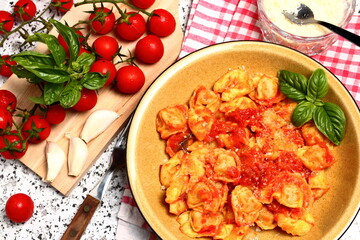 Delicious plate of tortellini topped with tomato sauce and basil. View from above.