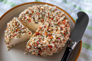 French cheese collection, fresh white soft goat cheese with aromatic herbs, garlic, parsley and red peppers close up