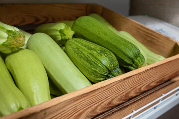 fresh zucchini squash, seasonal green vegetables in wooden box on grocery store shelf, local...