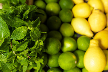fresh peppermint, lemons and limes in wooden box in grocery store or supermarket. Juicy ingredients for mojito or mohito long drink. Summer fruit for lemonade or desserts. Soft focus