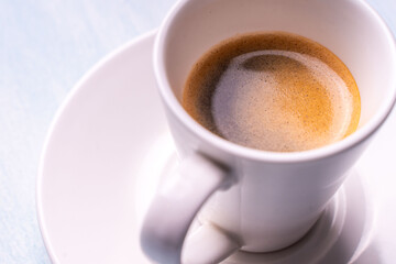 Black espresso coffee in a white cup and saucer on a light background.