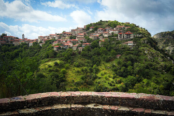 Dimitsana, a picturesque mountain village in Arkadia region, Peloponnese, Greece, nestled on a green hillside with traditional stone houses and red-tiled roofs.